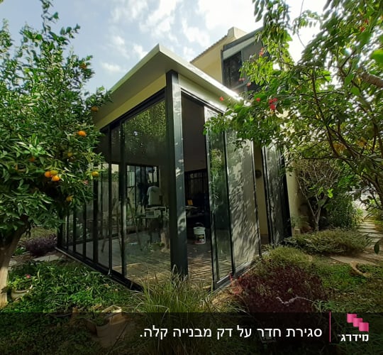 מבנה זכוכית עם מסגרות אלומיניום בגינה ירוקה